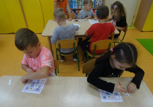 Dwoje dzieci układa sudoku i nakleja znaki na kartkę.
